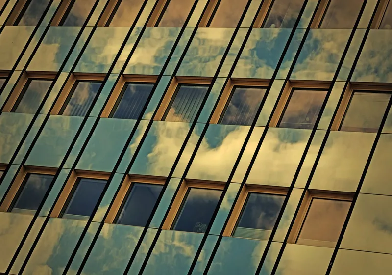 Zonlicht dat weerkaatst op een glasgevel met zonwerende raamfolie