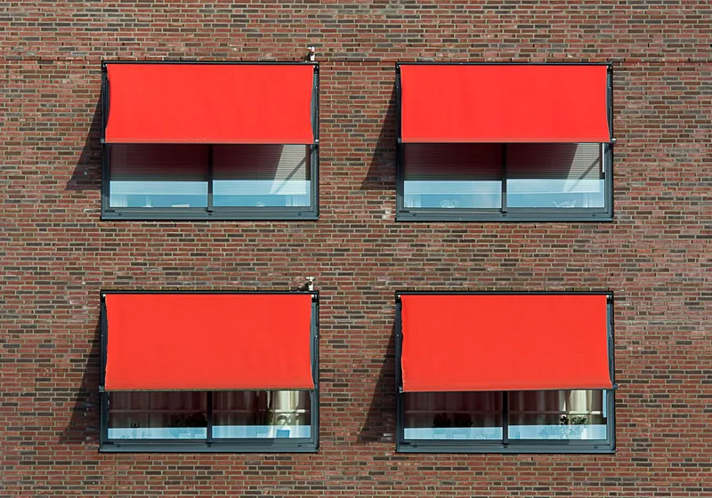 Gevel met strakke doekscreens voor de ramen die de zon buiten houden